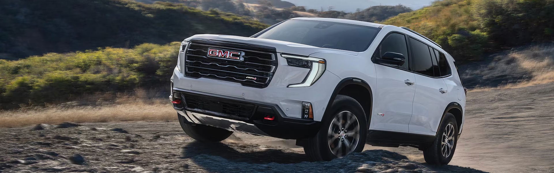 White GMC SUV driving on an off-road trail.